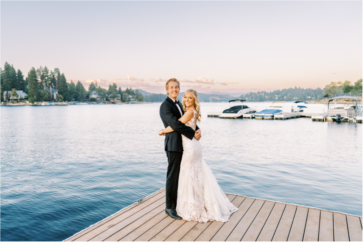 Bride and groom holding each other on dock at Lake Arrowhead at sunset