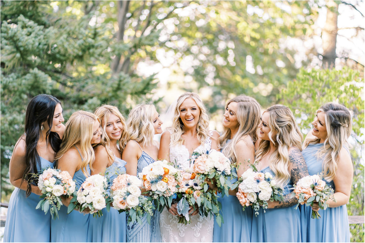 Bride with bridesmaids in blue dresses holding bouquets