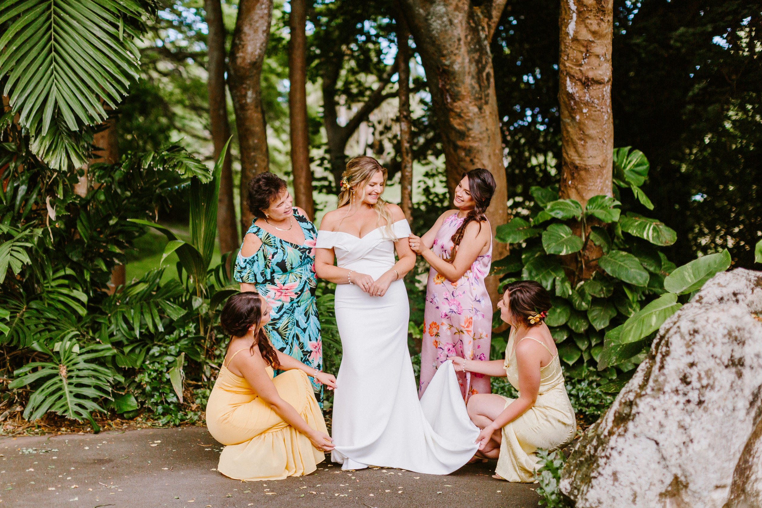 Bridesmaids helping bride get dressed in tropical venue