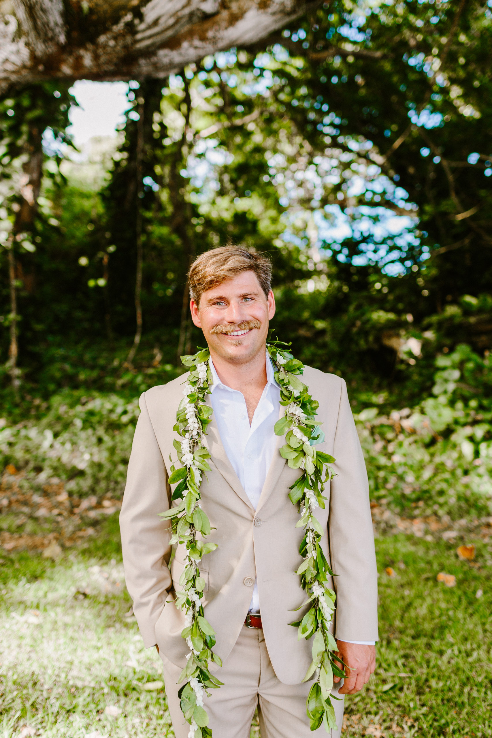 Groom in Hawaii wearing tan suit and maile lei