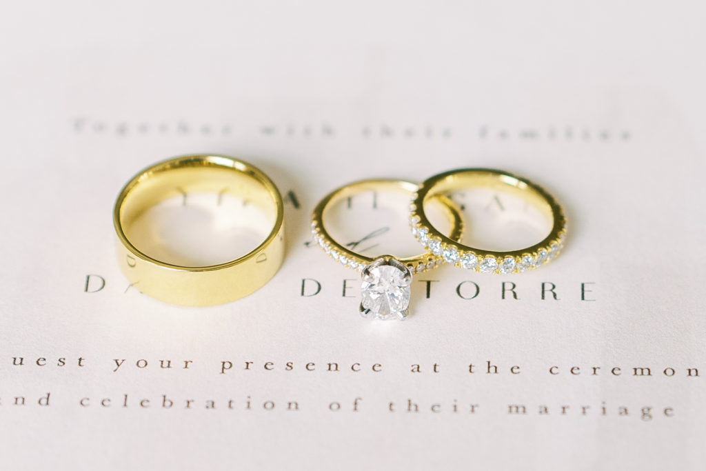 gold wedding ring bands on top of wedding invitation