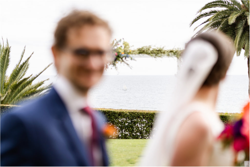 bride and groom looking at ocean with sailboat