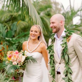 Bride and Groom wearing lei walking down aisle in Hawaii smiling