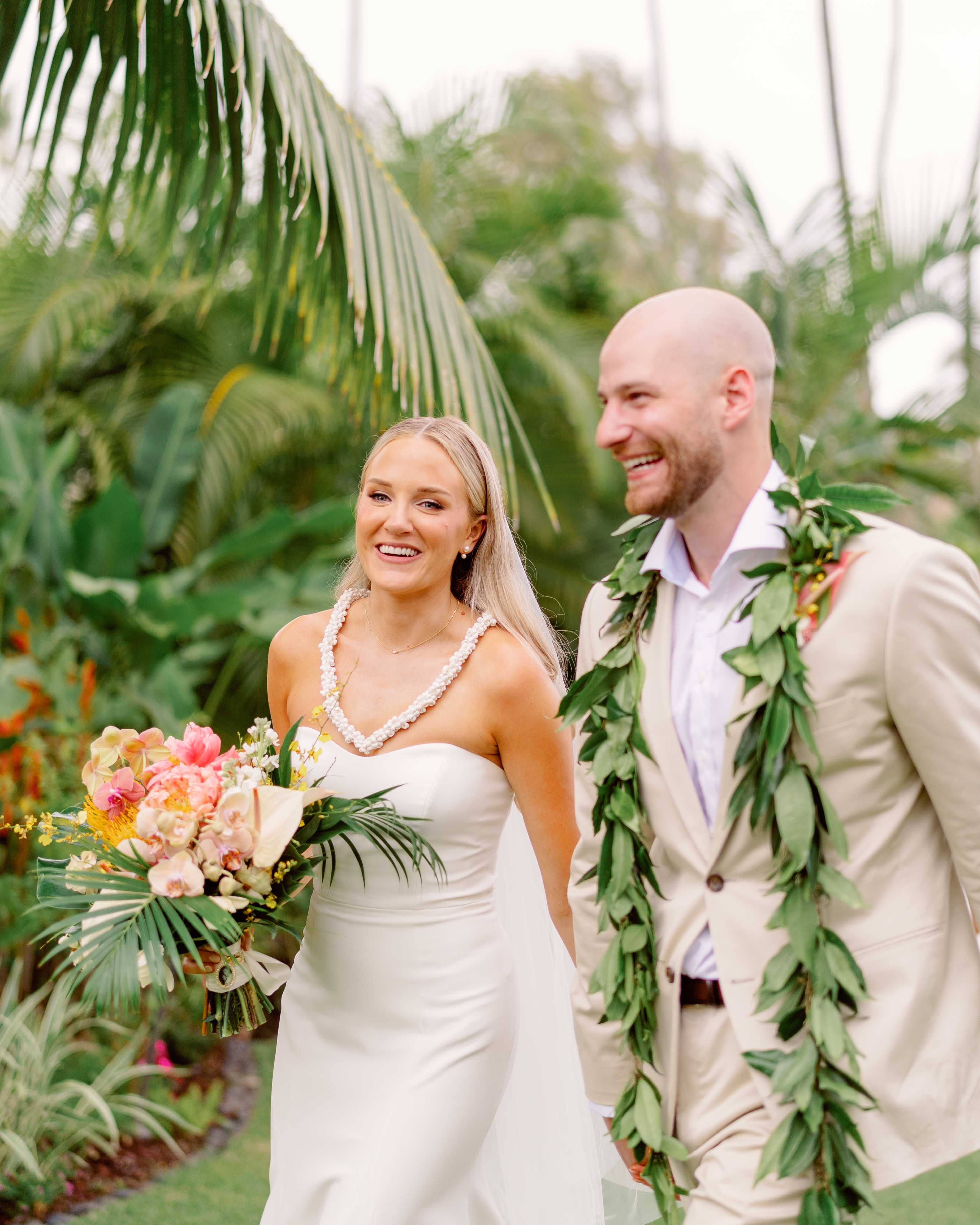 Bride and Groom wearing lei walking down aisle in Hawaii smiling