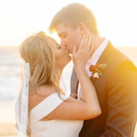 Bride kissing groom at sunset on the beach