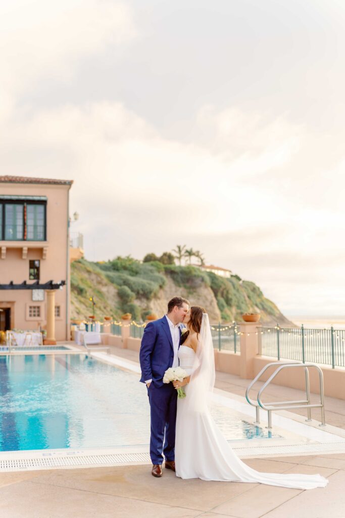 Bride and groom kissing in front of pool at Palos Verdes Beach Club